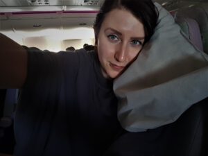 Frau mit Kissen und Decke im Flugzeug