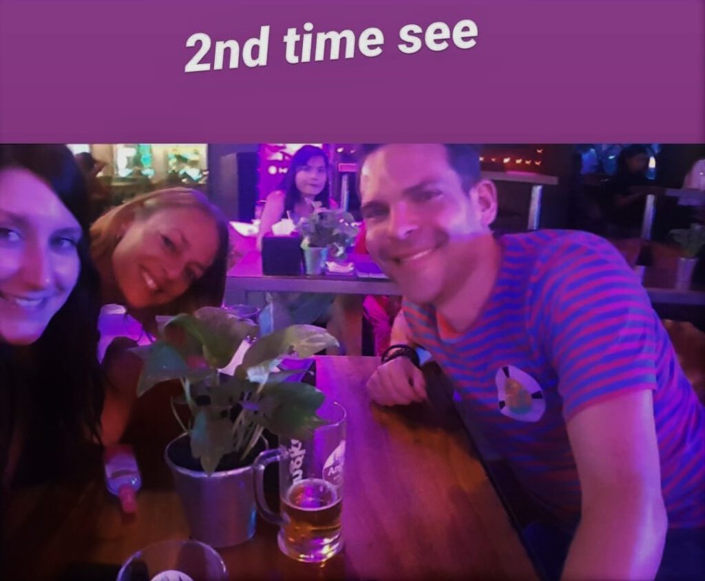2 Frauen und ein Mann am Tisch mit alkoholischen Getränken auf der Pub Street.