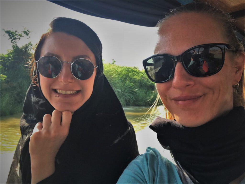 2 Frauen mit Sonnenbrille und einem Schal um den Kopf und Hals auf einem Boot