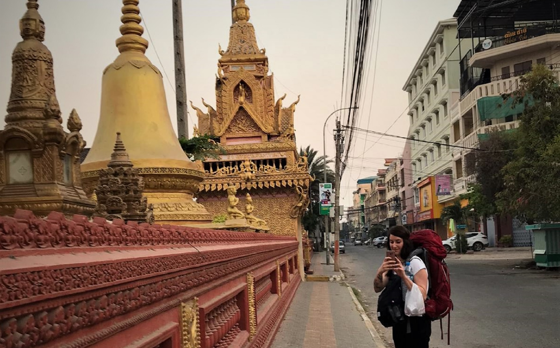 Frau mit Rucksack vor buddhistischem Kloster in Battambang am frühen Morgen